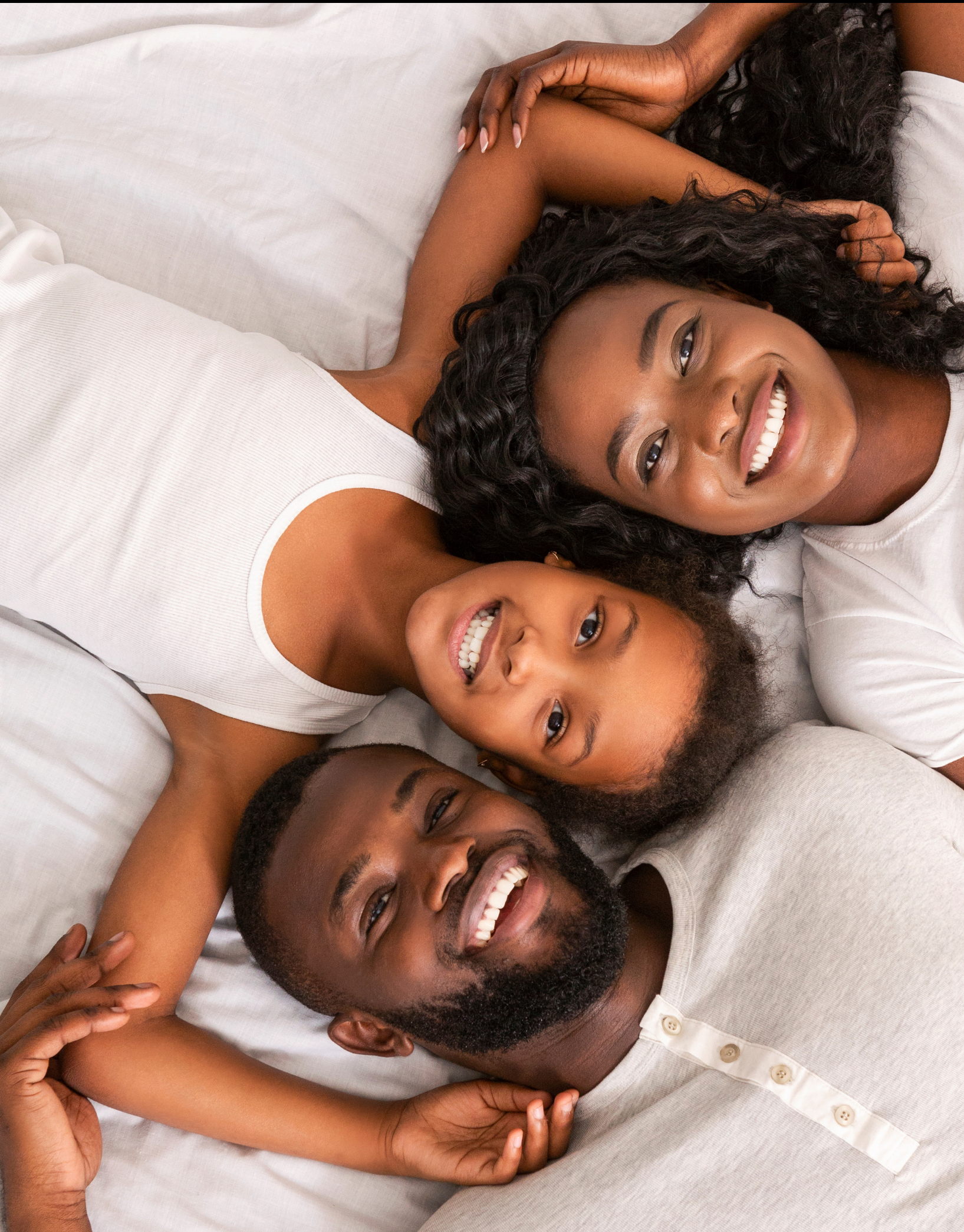 Top view of a man, woman and daughter laying in bed