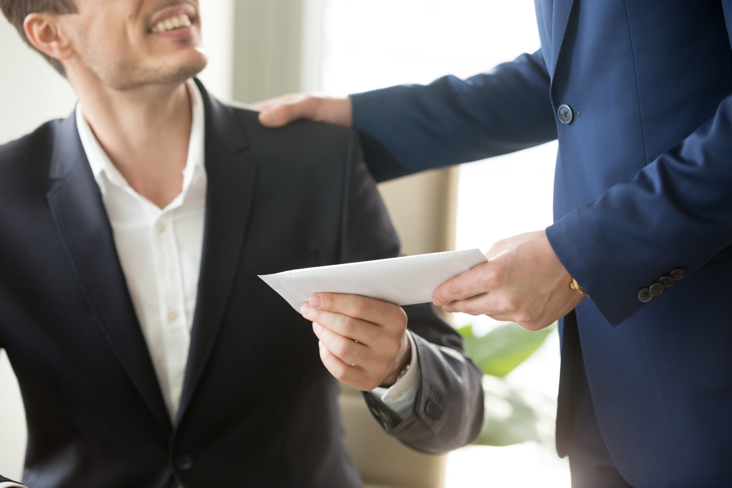 Well dressed man hands a paper to another well dressed man